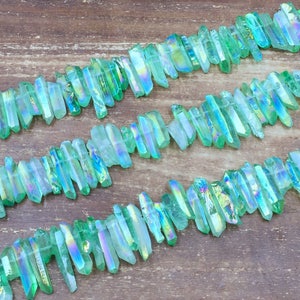 Peut inclure: Un brin de pointes de cristal vert irisé, également connu sous le nom de quartz aura d'ange, disposé en quinconce. Les cristaux sont translucides et ont un reflet arc-en-ciel.