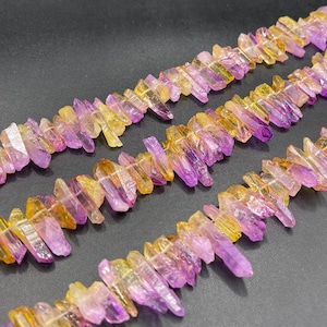 May include: A strand of purple and yellow crystal beads, each bead is a long, thin, pointed crystal. The crystals are arranged in a staggered pattern, creating a visually appealing design.