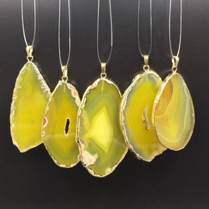 May include: Five yellow agate pendants with gold-toned accents. The pendants are on clear cords and are ready to be made into necklaces.