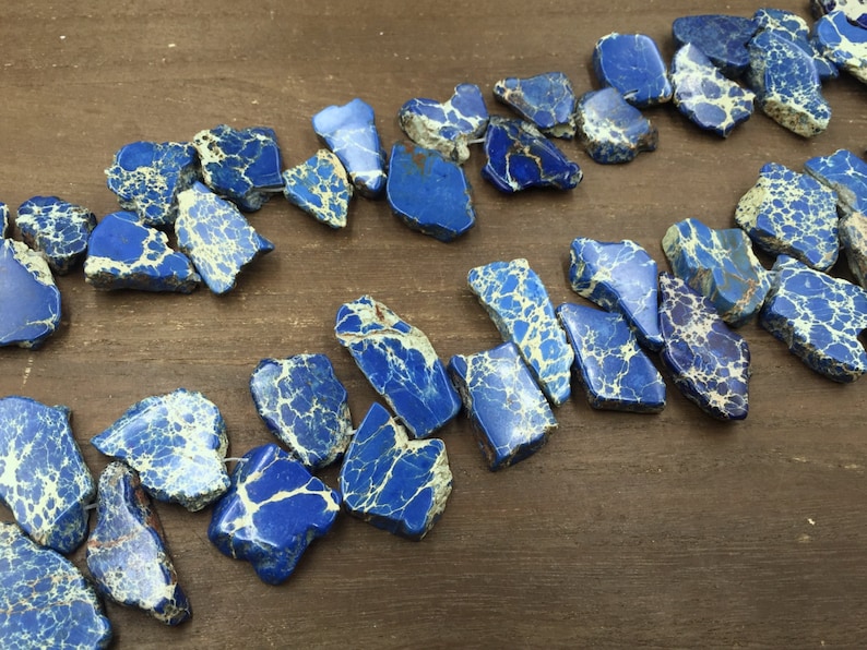 Pode incluir: Um fio de contas de jaspe azul e branco. As contas t&ecirc;m um formato irregular e um padr&atilde;o manchado.