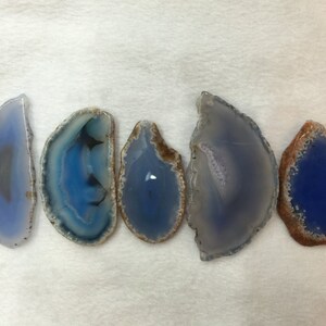 May include: Five agate slices with blue and white banding. The agate slices are polished and have a natural, organic shape.