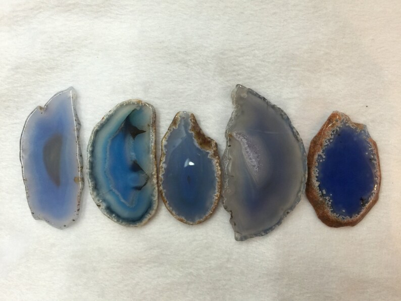 May include: Five agate slices with blue and white banding. The agate slices are polished and have a natural, organic shape.