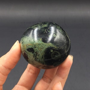 May include: A smooth, polished sphere of black and green serpentine stone. The stone has a swirling pattern of green and black.