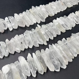 May include: A strand of clear quartz crystal points, also known as rock crystal, arranged in rows. The points are natural and have a raw, unpolished finish.
