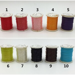 May include: Ten spools of thread in various colors, including red, pink, orange, purple, yellow, white, black, brown, and blue. The spools are labeled with numbers 1 through 10.