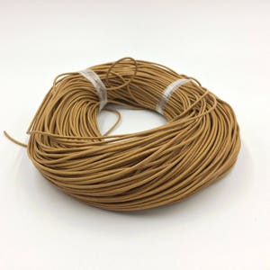 Puede incluir: Un carrete de cordón de cuero marrón, perfecto para proyectos de artesanía.