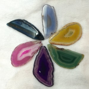 May include: Six agate slices in various colours, including purple, green, yellow, pink, and blue, arranged in a flower shape on a white background.
