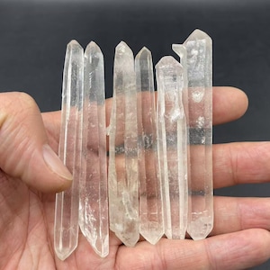 Puede incluir: Una colección de puntas de cristal de cuarzo transparente, también conocidas como cristales de roca, con un acabado natural y en bruto. Las puntas tienen diferentes longitudes y tienen una apariencia translúcida.