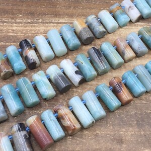 Pu&ograve; includere: Una collana di perle di pietra preziosa amazonite blu-verde, ogni perla &egrave; un cilindro con una finitura liscia e lucida. Le perle sono infilate su un cordoncino elastico trasparente.