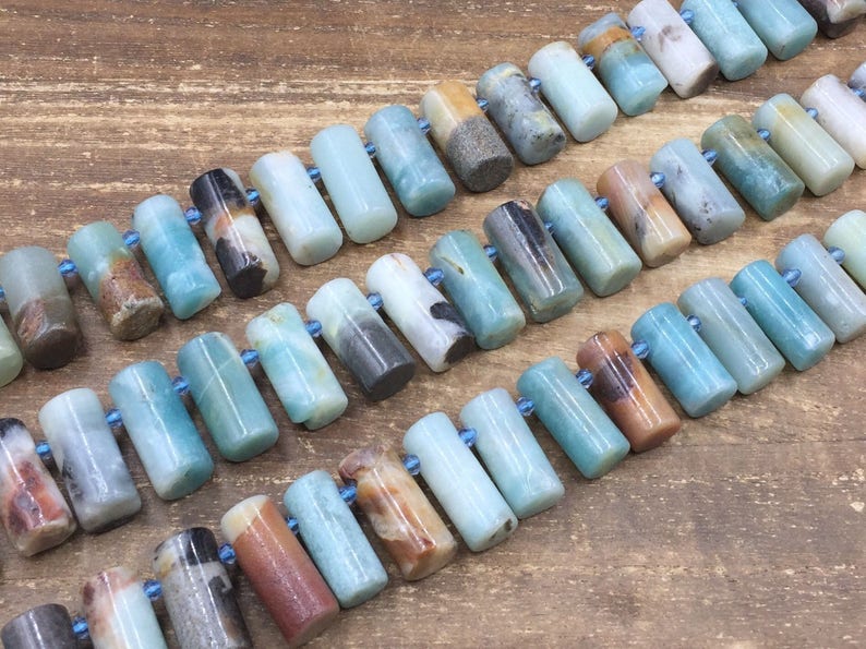 Pu&ograve; includere: Una collana di perle di pietra preziosa amazonite blu-verde, ogni perla &egrave; un cilindro con una finitura liscia e lucida. Le perle sono infilate su un cordoncino elastico trasparente.