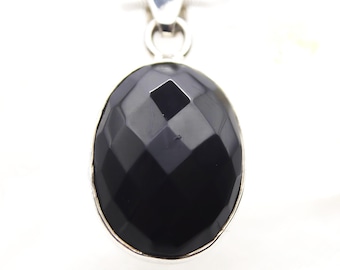 May include: An oval-shaped black onyx pendant featuring a faceted surface that creates geometric light reflections. The gemstone is set within a polished silver-toned metal frame and includes a matching silver-toned bail at the top for attachment.