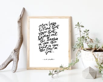 Pode incluir: Uma impressão emoldurada com fundo branco e texto em caligrafia preta que diz "You have to find that place that brings out the human in you. The soul in you. The love in you." O texto é atribuído a K.M. Drake.