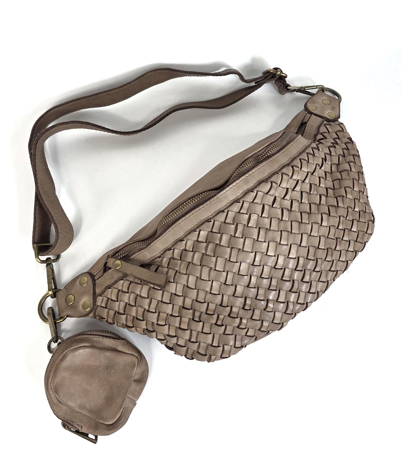 Puede incluir: Un bolso de cintura de cuero tejido de color topo con un peque&ntilde;o monedero a juego adjunto. El bolso tiene una correa larga ajustable y un cierre de cremallera. El bolso de cintura est&aacute; hecho de cuero suave y flexible.