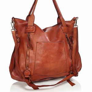 Eine cognac braune Ledertasche mit einer Vordertasche und zwei Reißverschlussfächern. Die Tasche hat zwei Schulterriemen und einen abnehmbaren Crossbody-Riemen. Das Leder hat einen Used-Look.