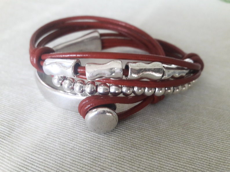 May include: A brown leather wrap bracelet with silver beads and metal accents.