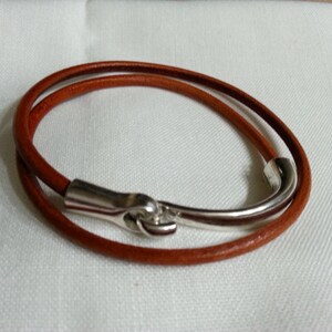 May include: A brown leather bracelet with a silver hook clasp.