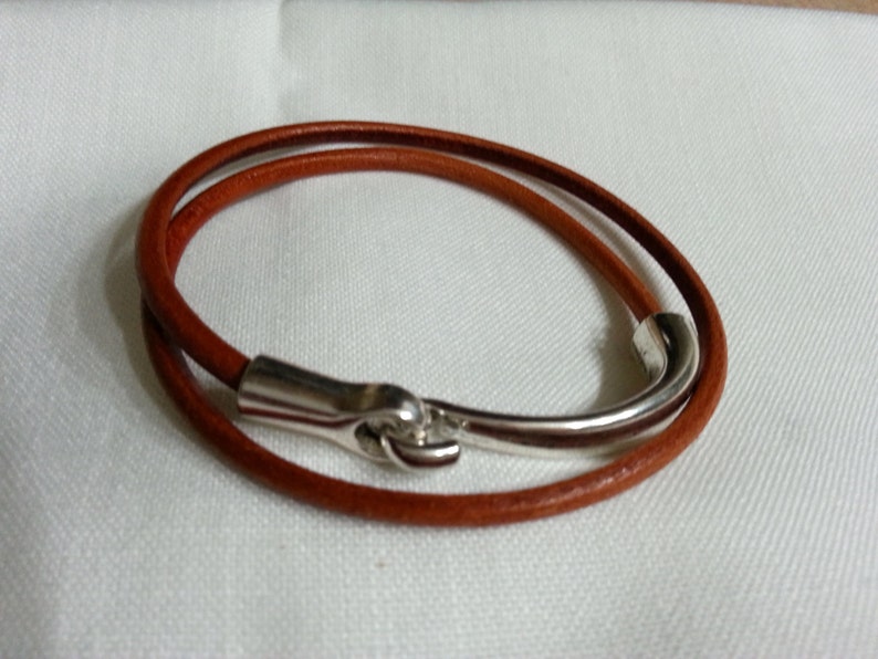 May include: A brown leather bracelet with a silver hook clasp.