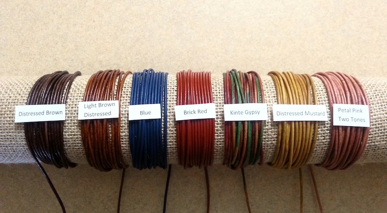 May include: Nine spools of leather cord in various colors, including distressed brown, light brown, blue, brick red, kinte gypsy, distressed mustard, and petal pink. Each spool is labeled with the color and description.