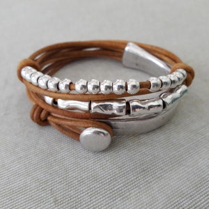 May include: A brown leather wrap bracelet with silver beads and metal accents.