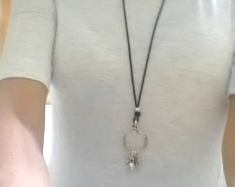 May include: A black cord necklace with a silver charm pendant featuring a circle and multiple smaller charms.