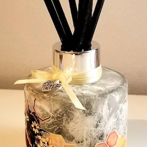 Peut inclure: Une bouteille diffuseur en verre transparent avec un couvercle argent&eacute; et des b&acirc;tonnets diffuseurs noirs. La bouteille est d&eacute;cor&eacute;e d'un motif en nid d'abeille et d'une illustration d'abeille. Un ruban jaune avec un charme de c&oelig;ur argent&eacute; est nou&eacute; autour du cou de la bouteille.