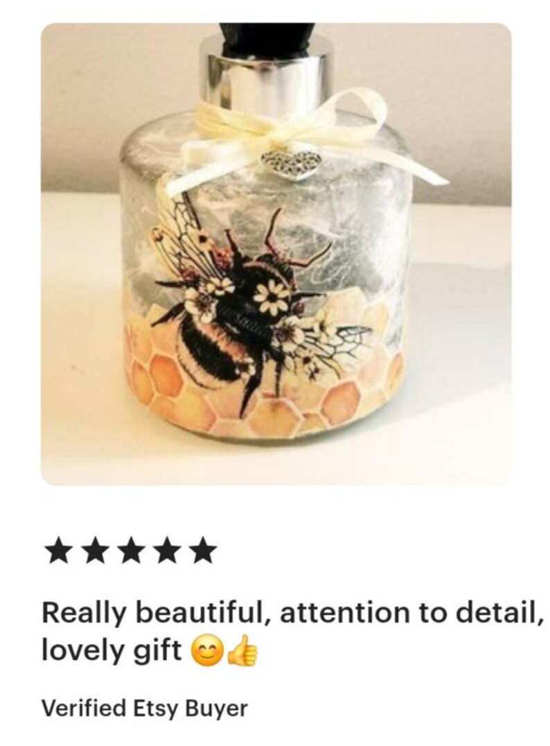 Peut inclure: Une bouteille en verre transparent avec un couvercle argent&eacute; et un ruban jaune. La bouteille est d&eacute;cor&eacute;e d'un motif d'abeille et de nid d'abeille avec des fleurs. La bouteille est un objet d&eacute;coratif.