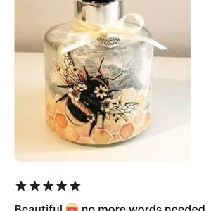 Peut inclure: Une bouteille en verre transparent avec un couvercle argent&eacute; et un ruban jaune. La bouteille pr&eacute;sente un motif d'abeille et de nid d'abeille avec une abeille noire et jaune et un charme de c&oelig;ur blanc sur le ruban.
