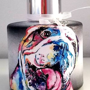 Peut inclure: Une bouteille de diffuseur en verre noir avec un couvercle argenté et un ruban blanc. La bouteille présente une illustration aquarelle colorée du visage d'un bouledogue.