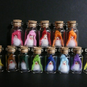 May include: A collection of 14 small glass bottles with cork tops, each containing a felt gnome wearing a colourful hat. The gnomes are wearing hats in various colours, including pink, red, orange, yellow, green, blue, and purple.