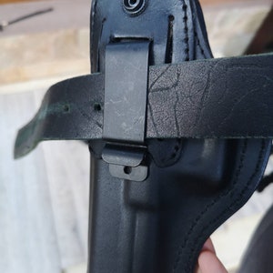 Puede incluir: Funda de cuero negra con un bucle para el cintur&oacute;n y un clip de metal. La funda est&aacute; dise&ntilde;ada para sostener una pistola.