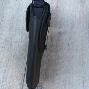 Puede incluir: Funda de cuero negro para una pistola. La funda tiene una solapa que asegura el arma en su lugar.