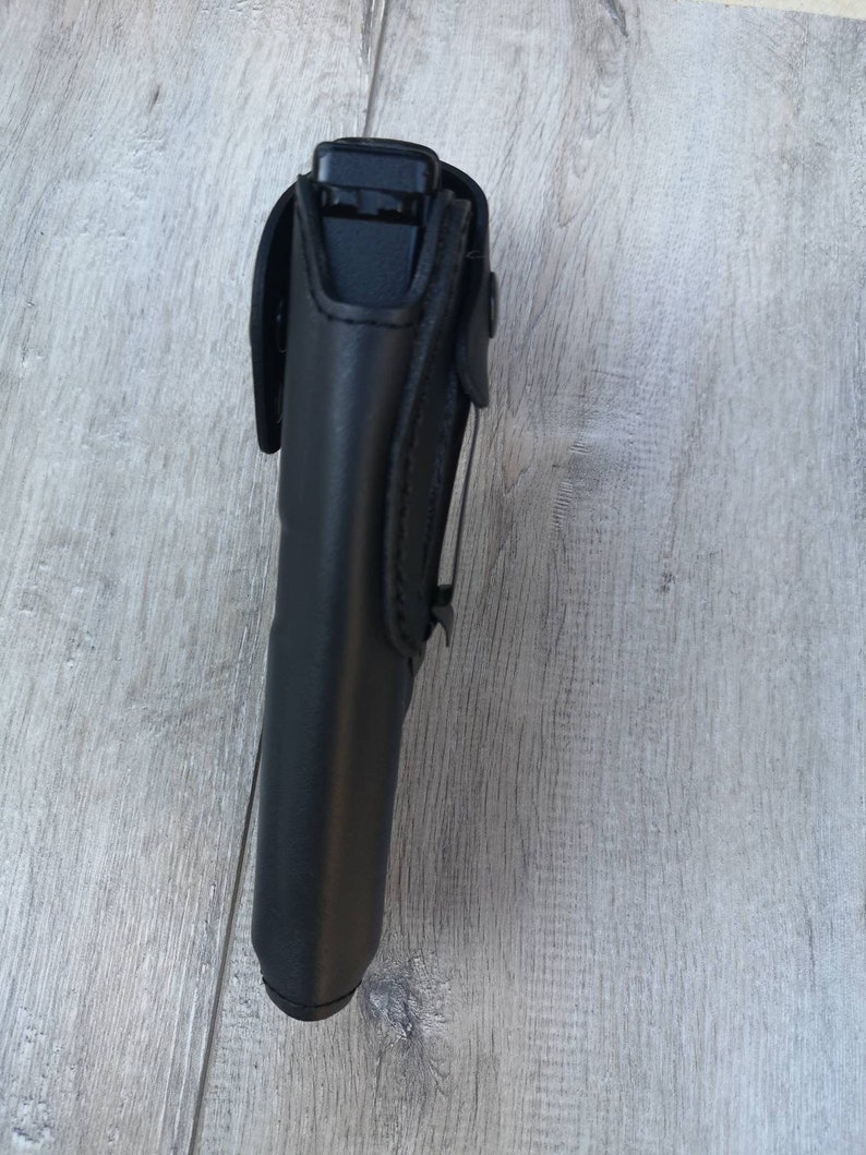 Puede incluir: Funda de cuero negro para una pistola. La funda tiene una solapa que asegura el arma en su lugar.