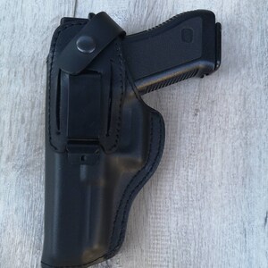 Puede incluir: Una funda de cuero negra para una pistola con un clip en el lateral.