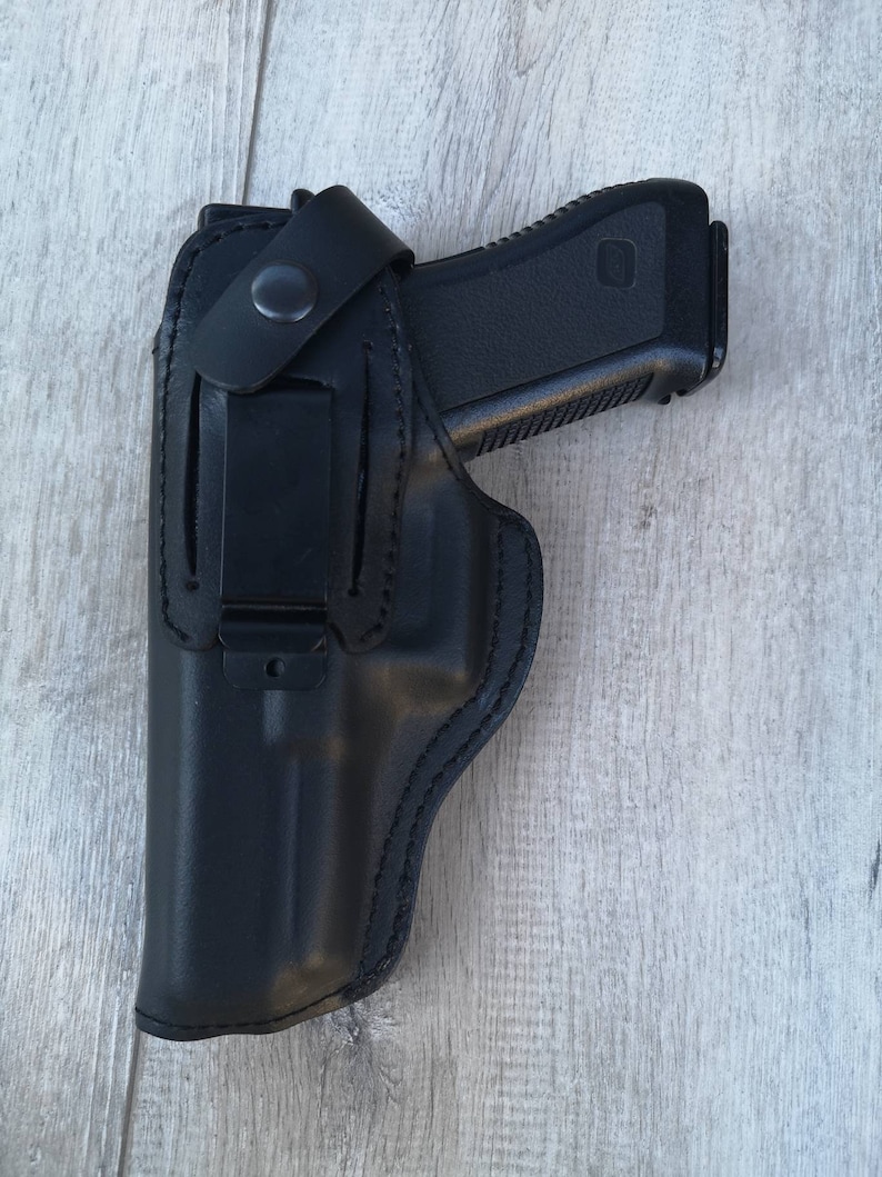Puede incluir: Una funda de cuero negra para una pistola con un clip en el lateral.