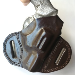 May include: A brown leather holster for a small handgun. The holster has a belt loop and a snap closure.