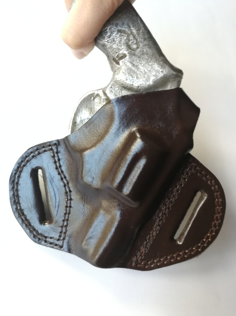 May include: A brown leather holster for a small handgun. The holster has a belt loop and a snap closure.