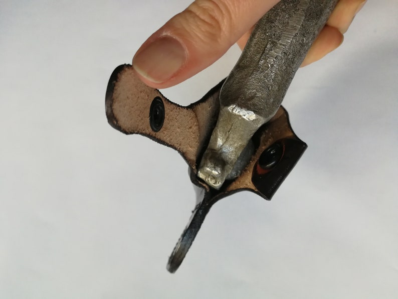 May include: A brown leather case with a metal object inside. The case has two black snaps.