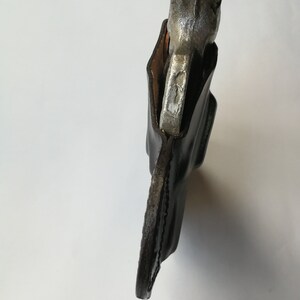 May include: A brown leather holster with a silver metal object inside. The holster is designed to hold a small tool or weapon.