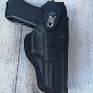 Puede incluir: Una funda de cuero negra para una pistola. La funda tiene un bucle para el cintur&oacute;n y un cierre a presi&oacute;n.