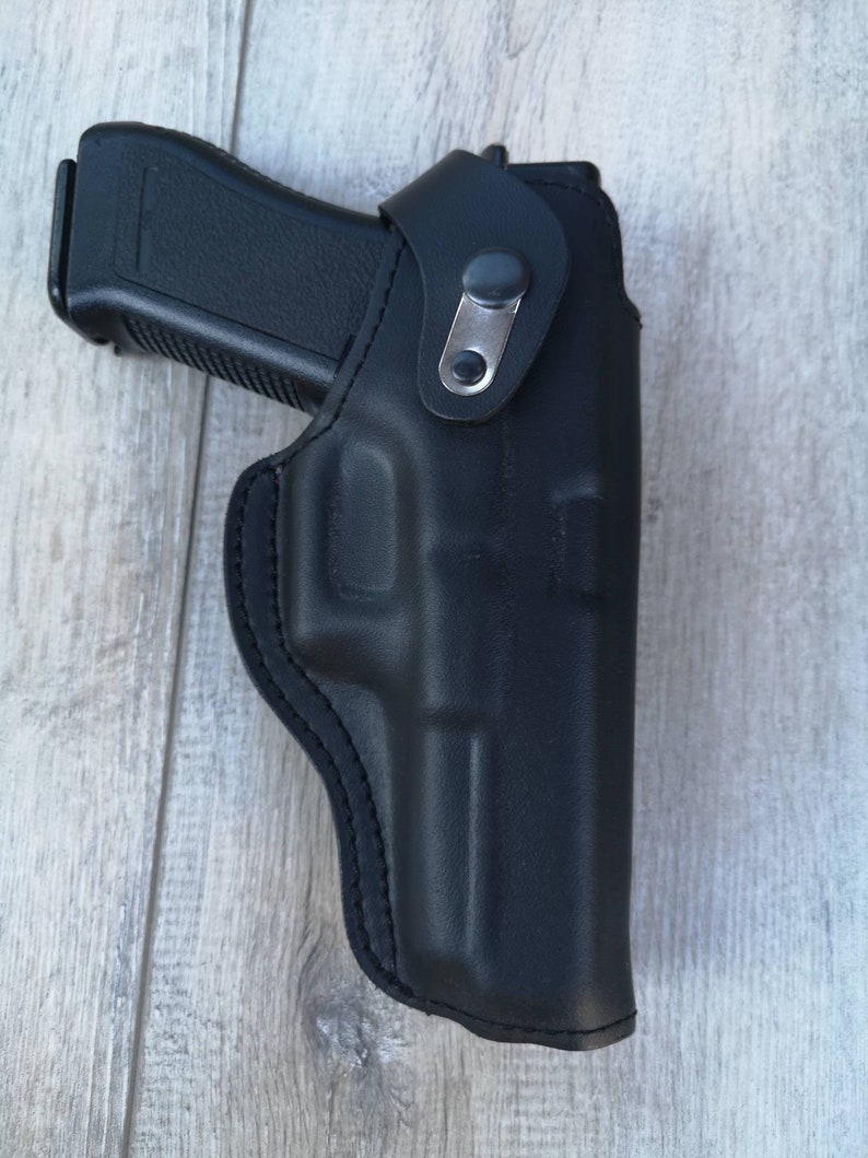 Puede incluir: Una funda de cuero negra para una pistola. La funda tiene un bucle para el cintur&oacute;n y un cierre a presi&oacute;n.