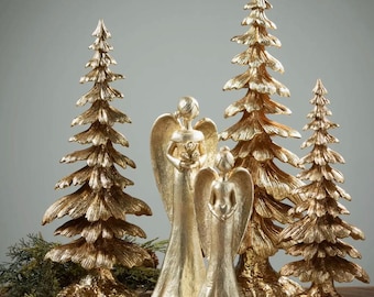 May include: Gold-toned angel figurines and stylized pine tree ornaments. The angels are holding flowers and have wings. The trees are detailed with textured bark and branches.