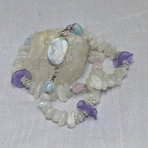 May include: A white, blue, and pink gemstone necklace with a silver pendant featuring a white, blue, and pink swirl design.