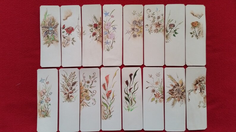 Puede incluir: Conjunto de 16 marcap&aacute;ginas en blanco con dise&ntilde;os florales pintados a mano. Cada marcap&aacute;ginas presenta un motivo floral diferente en tonos rojos, azules, amarillos y verdes.