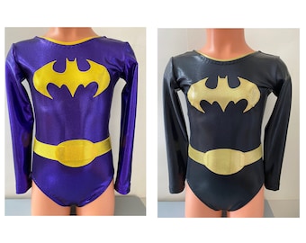 May include: Two long-sleeved leotards with a bat symbol and a gold belt. One leotard is purple and the other is black.