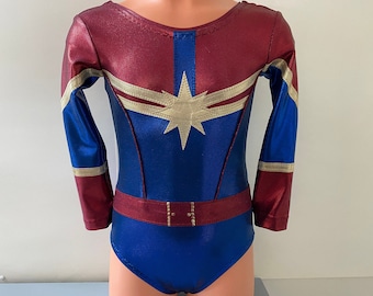 May include: A red and blue leotard with gold accents and a star design. The leotard has long sleeves and a belt.
