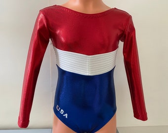 May include: Red, white and blue long-sleeved leotard with a white stripe across the chest and the word "USA" on the bottom.