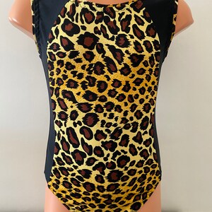 Puede incluir: Un leotardo de estampado de leopardo negro y amarillo con tirantes negros sin mangas y cuello redondo.