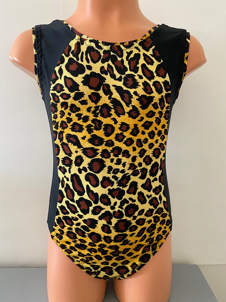 Puede incluir: Un leotardo de estampado de leopardo negro y amarillo con tirantes negros sin mangas y cuello redondo.