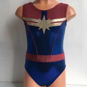 May include: A blue and maroon leotard with a gold star and two gold stripes. The leotard has a maroon belt with gold accents.