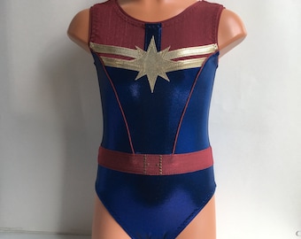 May include: A blue and maroon leotard with a gold star and two gold stripes. The leotard has a maroon belt with gold accents.